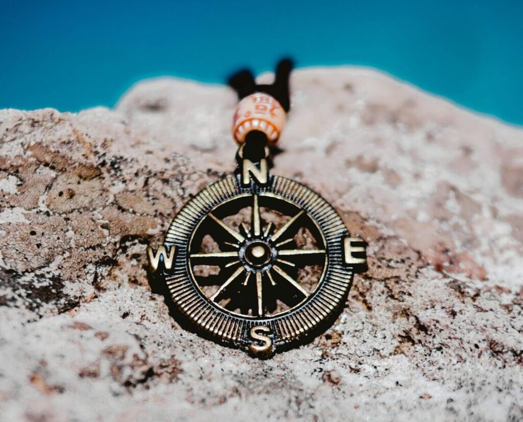 compass From above of stylish metal pendant in shape of compass placed on white rock